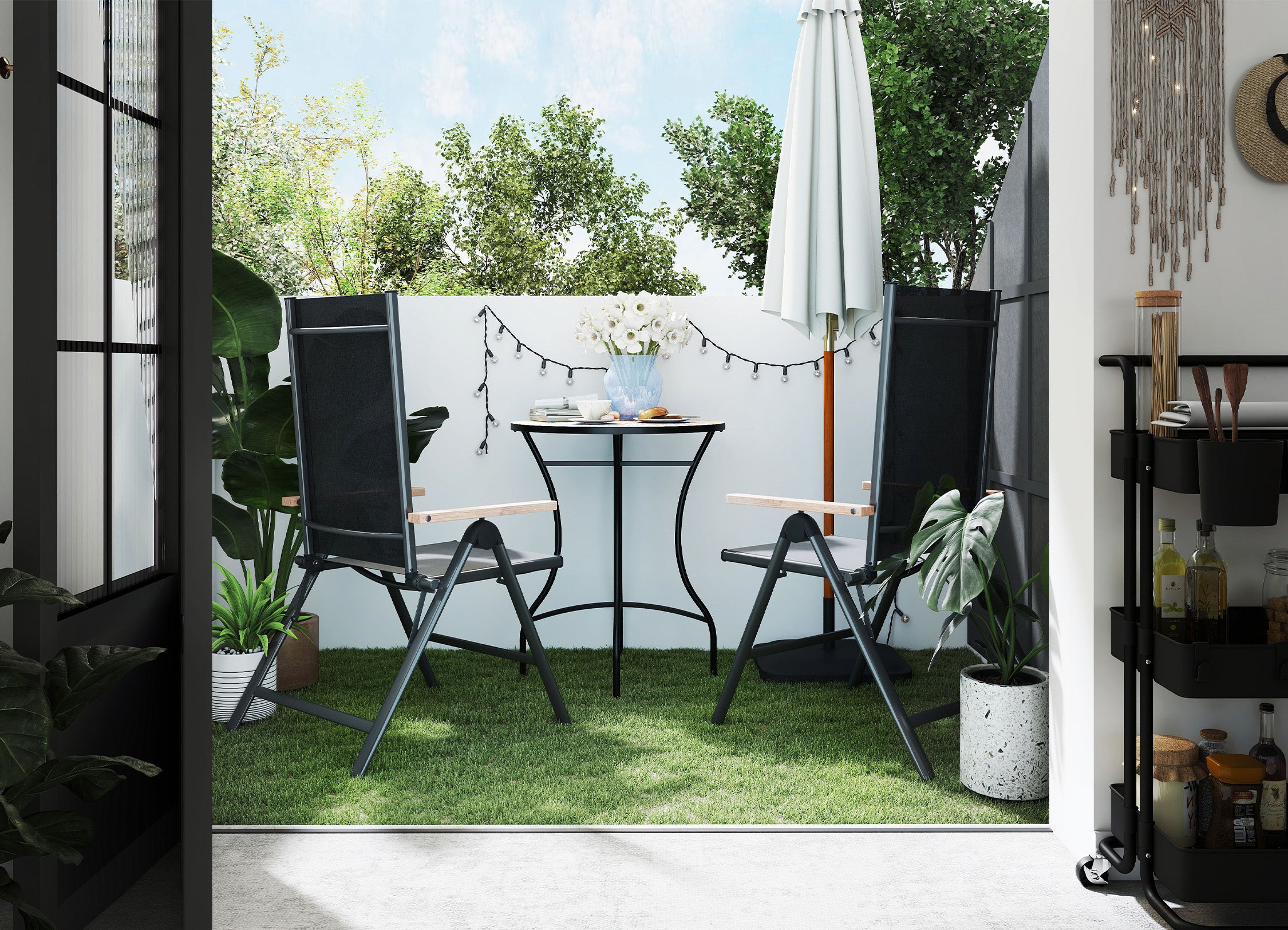 Outdoor patio area with black chairs, table, and umbrella in a garden setting.