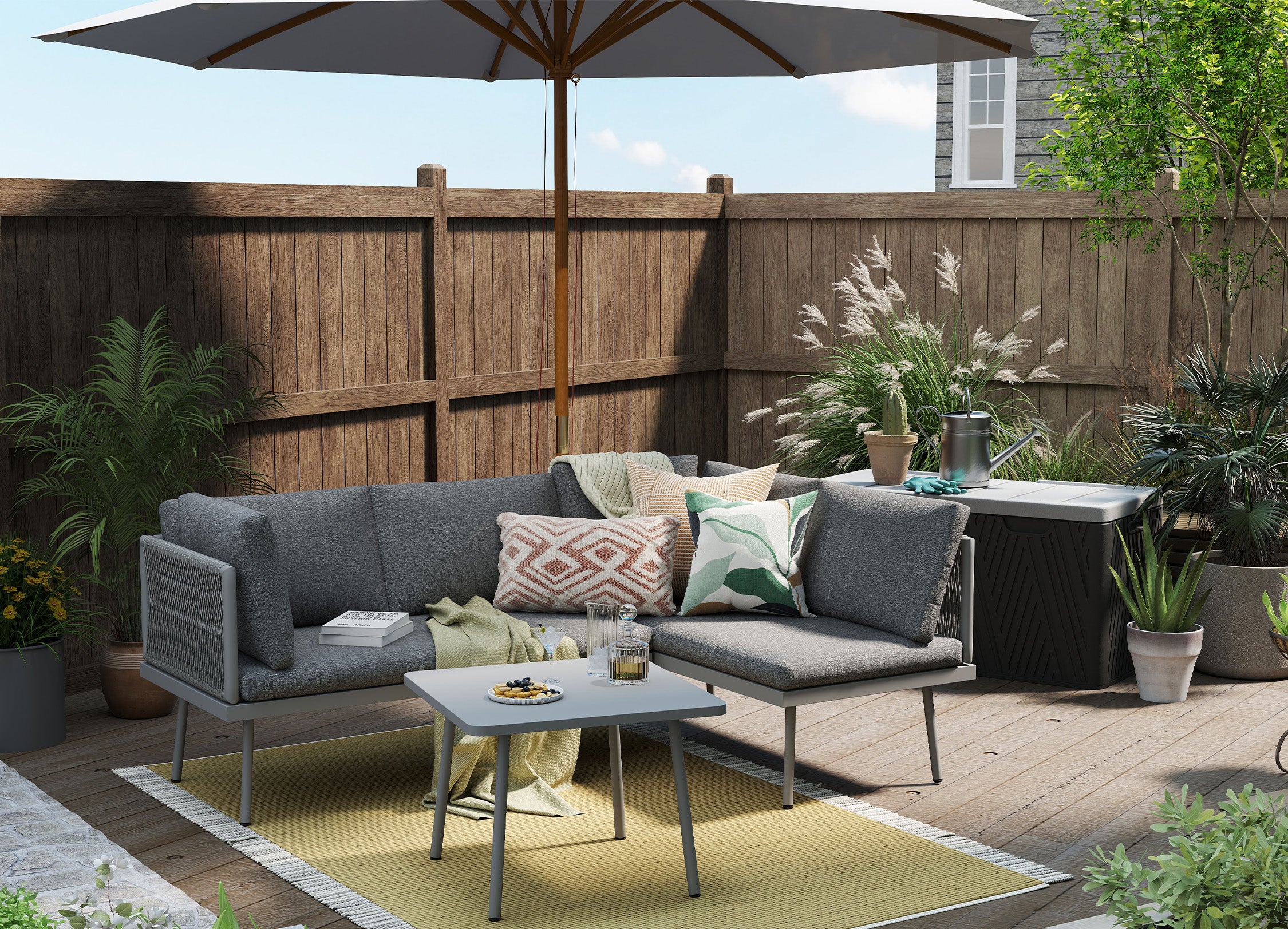 Outdoor patio with gray sectional sofa, coffee table, and umbrella on a wooden deck.