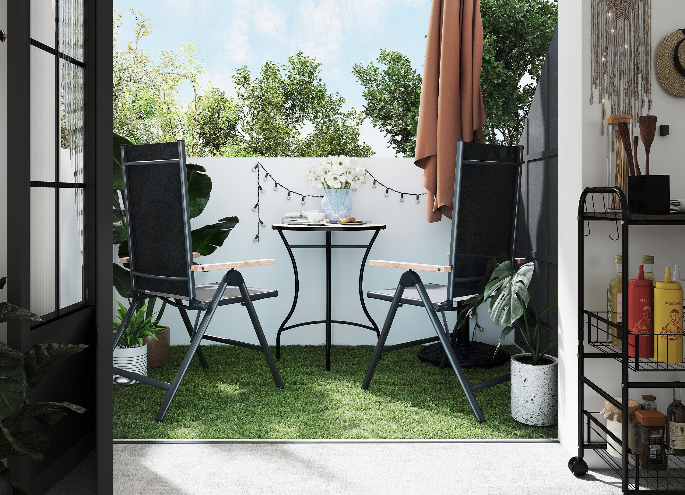 Outdoor patio area with black chairs, table, and plants on a grassy patch.